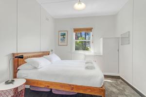 a bedroom with a large white bed with a window at Swim Two Birds in Erowal Bay