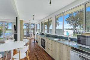 a kitchen with large windows and a table and chairs at Swim Two Birds in Erowal Bay
