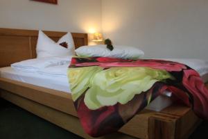 a bed with a colorful blanket on top of it at Hotel Grüner Baum in Stollberg