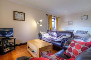 a living room with a leather couch and a tv at Shilbury Retreat Cottage in Perranporth