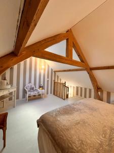 a attic bedroom with a bed and a table at La Grange Aux Hirondelles - Chambre romantique in Woignarue