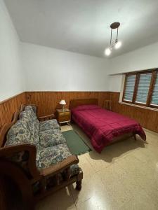 a bedroom with a bed and a couch in it at Casa con pileta in Tandil +5 photos