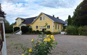 una casa amarilla con flores amarillas delante de ella en Hotell Vita Hästen Hästveda, en Hästveda