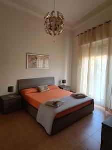 a bedroom with a bed with orange sheets and a chandelier at Charme in Aci Castello in Aci Castello