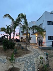 a building with palm trees in front of it at Villas Del Scarlet Cardones in Pescadero