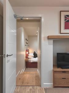 a bedroom with a bed and a door with a television at Y Cwtch Cottage By Birch Stays in Rhosneigr