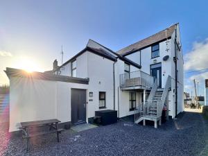 a white building with a bench in front of it at Y Cwtch Cottage by Birch Stays in Rhosneigr