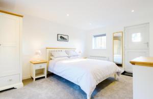ein weißes Schlafzimmer mit einem Bett und einem Spiegel in der Unterkunft Ivy Chimney Cottage in Porthtowan