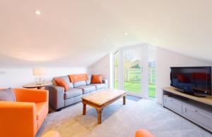 ein Wohnzimmer mit einem Sofa und einem TV in der Unterkunft Ivy Chimney Cottage in Porthtowan
