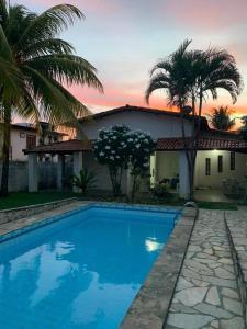 une piscine bleue en face d'une maison dans l'établissement Casa de Veraneio com Piscina Perto da Praia, à Lauro de Freitas