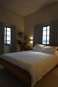 1 Schlafzimmer mit einem großen Bett und 2 Fenstern in der Unterkunft MORI HOUSE in Bet Scheʼan