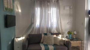 uma sala de estar com um sofá em frente a uma janela em Familia Rodrigues no Guarujá