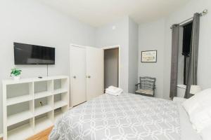 a white bedroom with a bed and a flat screen tv at Parking - Walkable - GroupStays - Washer in Pittsburgh