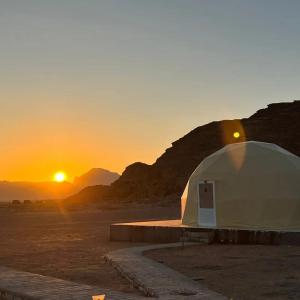 une tente dans le désert avec le coucher du soleil en arrière-plan dans l'établissement Wadi Rum Classic camp, à Aqaba