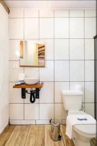 a bathroom with a toilet and a sink at Prumirim Surf Suítes in Ubatuba