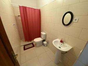 a bathroom with a red shower curtain and a sink at Pousada Cantinho de Preta in Seladinha