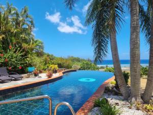 basen z palmami i plażą w obiekcie Black Rock Villas w mieście Rarotonga
