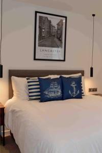 1 cama con almohadas azules y blancas y una foto en la pared en Riverside House Lancaster - 2 bedroom house, en Lancaster