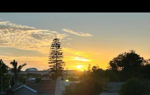 un coucher de soleil avec un arbre et le soleil dans le ciel dans l'établissement G’s Self Catering Apartments, au Cap