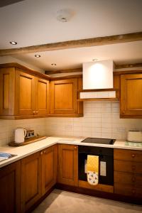 uma cozinha com armários de madeira e um forno com placa de fogão em Gardener's Cottage em Lancaster