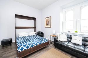 ein Schlafzimmer mit einem Bett und einem Ledersofa in der Unterkunft ROKU TVs - Washer & Dryer - QueenBeds - GroupStay in Pittsburgh