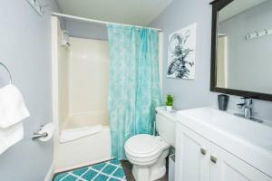 a bathroom with a white toilet and a blue shower curtain at ROKU TVs - Washer & Dryer - QueenBeds - GroupStay in Pittsburgh +18 photos