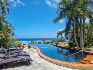 una piscina en un complejo con sillas y palmeras en Black Rock Villas en Rarotonga
