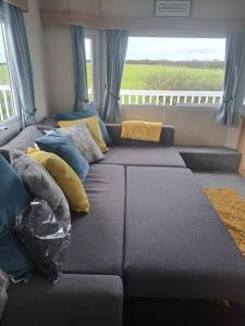 a living room with a couch with pillows and a window at Cosy home with stunning views in Holsworthy