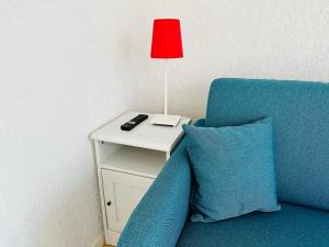 een rode lamp op een bijzettafel naast een blauwe bank bij La crevette grise à Cayeux sur mer en baie de Somme in Cayeux-sur-Mer