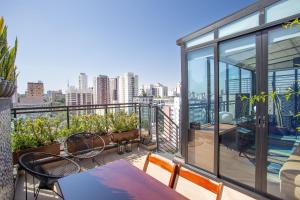 balcón con mesa, sillas y vistas a la ciudad en Living Design Vila Madalena, en São Paulo