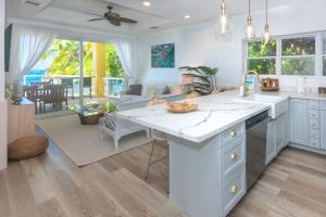 a kitchen with white counter tops and a living room at Del Playa #2 Condo in West End