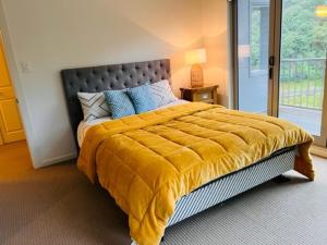 a bedroom with a large bed with a yellow blanket at Villa Sebastian - Large Modern Home in Wellington