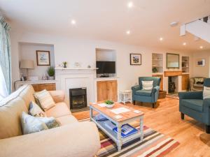 a living room with a couch and chairs and a fireplace at Nutwood in Charmouth