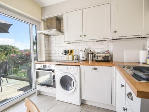 a kitchen with white cabinets and a washer and dryer at Nutwood in Charmouth