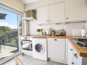 a kitchen with white cabinets and a washer and dryer at Nutwood in Charmouth