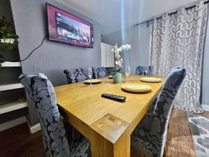 mesa de comedor con sillas y TV en la pared en 4 bedroom Hse close to Riverside en Gravesend