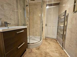 y baño con ducha, lavabo y puerta de ducha acristalada. en 4 bedroom Hse close to Riverside en Gravesend