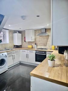 una cocina con armarios blancos y una planta en un mostrador en 4 bedroom Hse close to Riverside, en Gravesend