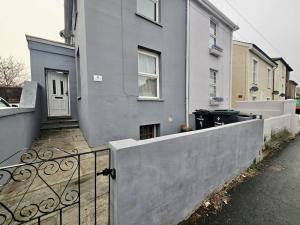 una casa grigia con una recinzione e una porta di 4 bedroom Hse close to Riverside a Gravesend