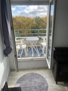 uma vista para uma varanda com uma mesa e cadeiras em Appartement cosy en plein centre-ville em Évry-les-Châteaux