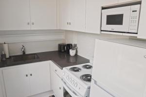 a white kitchen with a stove and a microwave at The Trafalgar in Oakville
