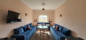 Maison Mamdy في مراكش: غرفة معيشة مع أريكة زرقاء وطاولة
