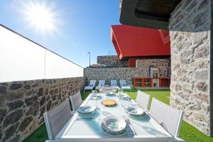 una mesa de comedor y sillas en un patio con una pared de piedra en Villa Cacemar Salobre, en Las Palmas de Gran Canaria