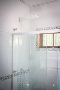 a white bathroom with a shower and a window at Chalé Sol da Montanha em Termas do Gravatal - SC in Gravatal