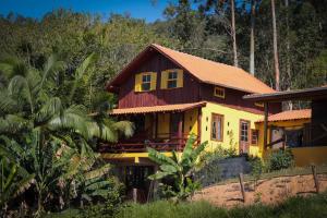a yellow house with a red roof at Chalé Sol da Montanha em Termas do Gravatal - SC in Gravatal