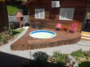 a wooden deck with a swimming pool and two chairs at Chalé Sol da Montanha em Termas do Gravatal - SC in Gravatal