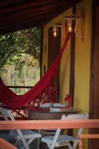 a red hammock hanging from a room with a table and chairs at Chalé Sol da Montanha em Termas do Gravatal - SC in Gravatal