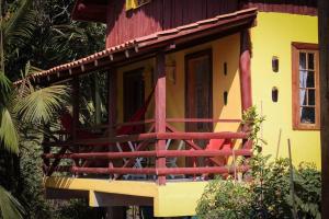 a small yellow and red house with a porch at Chalé Sol da Montanha em Termas do Gravatal - SC in Gravatal