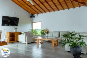 a living room with couches and a table and a tv at El Encanto de las Aguas in Necoclí