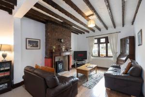 sala de estar con muebles de cuero y chimenea en Linden Cottage en Coxhoe